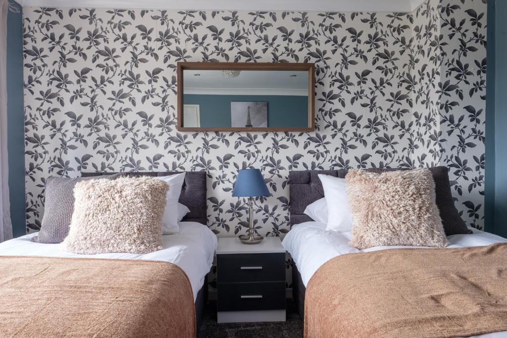 2 camas en un dormitorio con espejo en la pared en Modern & Elegant 3BR 15mins close to Gatwick- Dickens House en Crawley