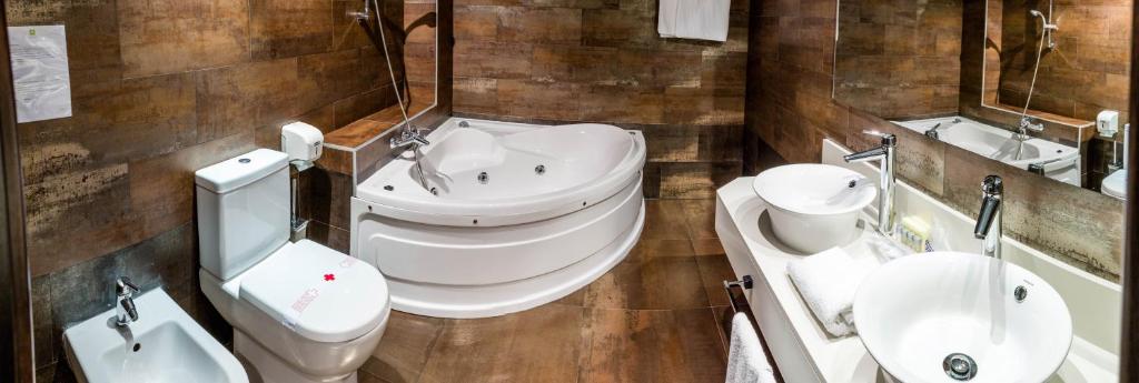 y baño con lavabo, aseo y bañera. en Hospedium Hotel Los Periquitos, en Fortuna