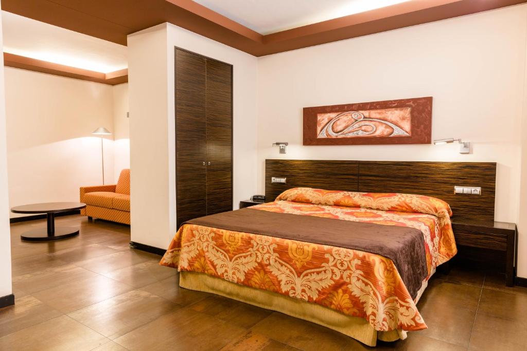 フォルトゥナにあるHospedium Hotel Los Periquitosのベッドと椅子付きのホテルルーム