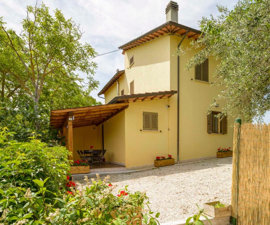 a large yellow house with a fence and trees at Casa vacanze San Vittorino in Gubbio