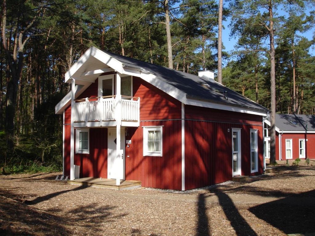 ein rotes Haus mit einem Balkon an der Seite in der Unterkunft Strandhaus Deichkrone in Baabe