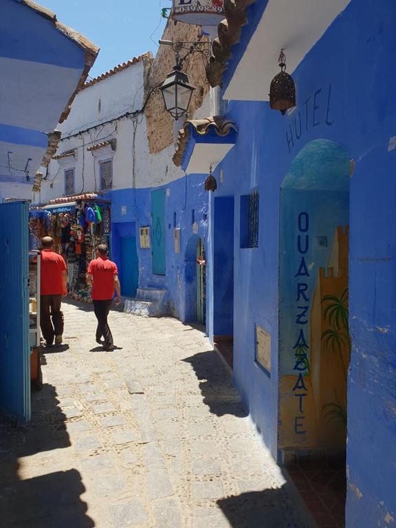 a man walking down a alley in a blue building at Hotel Ouarzazate in Chefchaouene