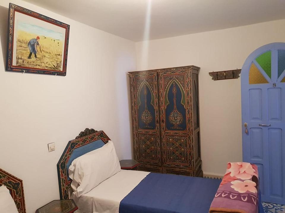a bedroom with a bed and a blue door at Hotel Ouarzazate in Chefchaouene