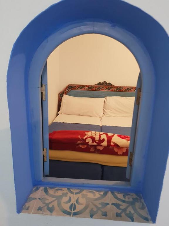 a small bedroom with a bed in a blue frame at Hotel Ouarzazate in Chefchaouene