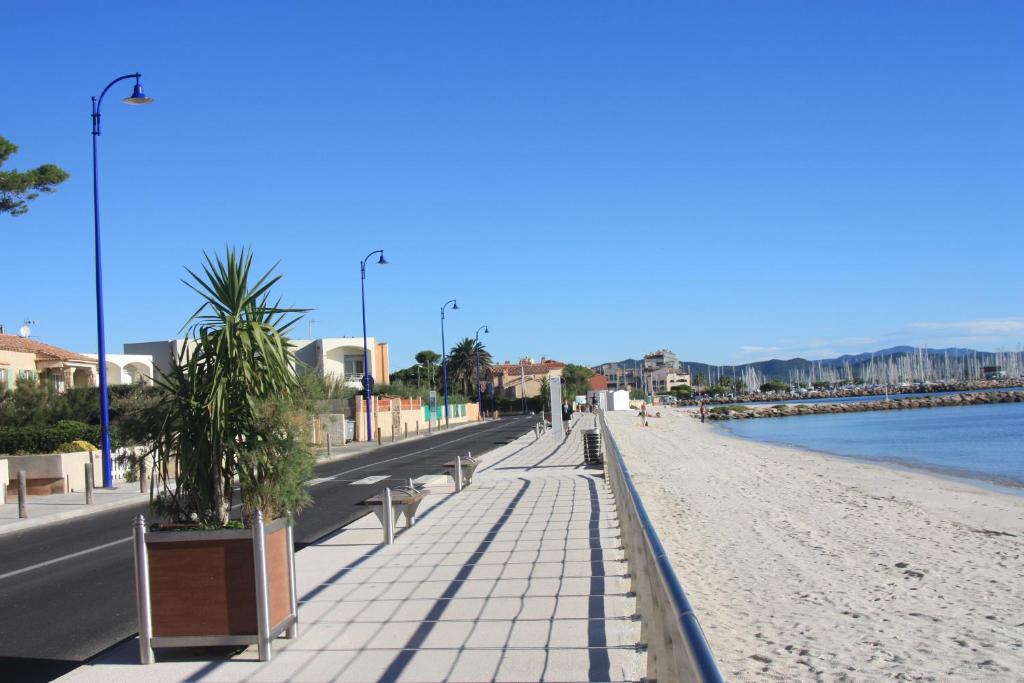 a beach with benches and trees on it next to the water at Les Stoechades in Hyères
