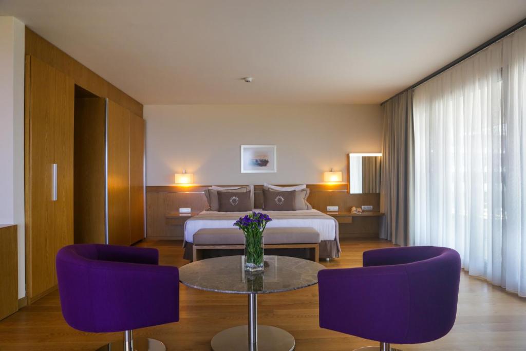 a hotel room with a bed and a table with purple chairs at ON'LIVE HOTEL in Çeşme