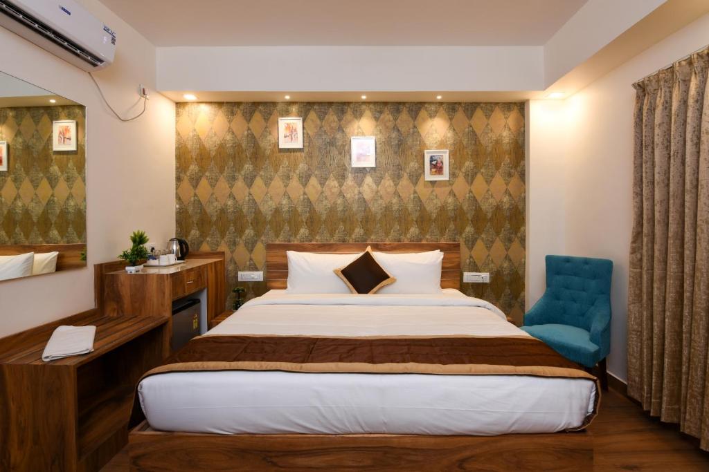 a hotel room with a bed and a blue chair at Kensington Suites in Bangalore