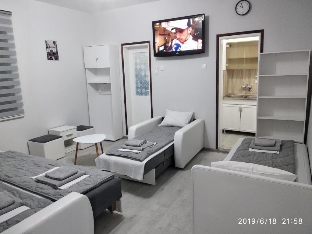 a room with two beds and a tv on the wall at Apartmani Pinokio in Niš