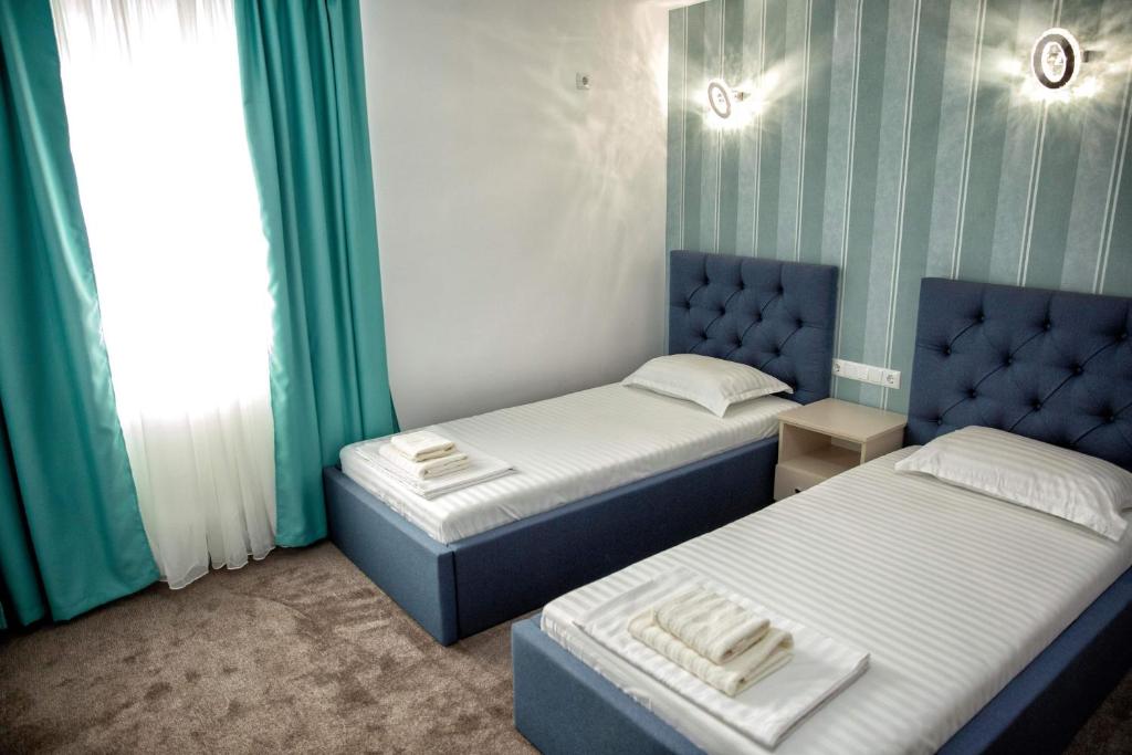 two beds in a room with green and white walls at Pensiunea Beny in Târgu Jiu