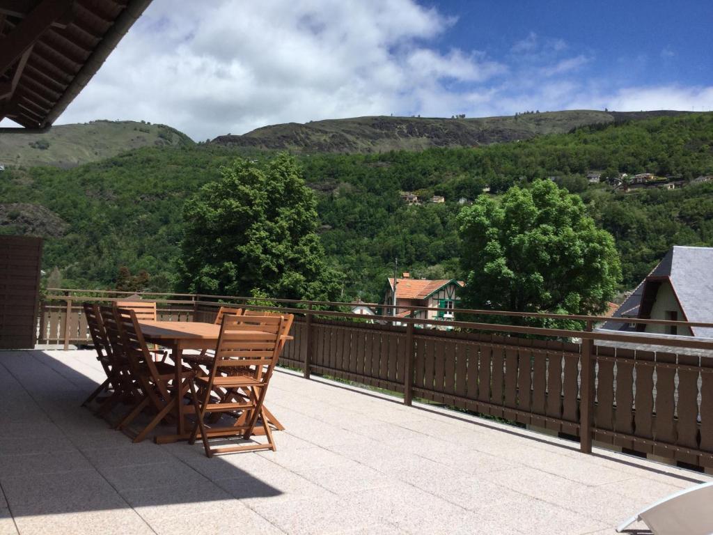 a wooden table and chairs on a balcony with mountains at Au chalet des quatre saisons in Ax-les-Thermes