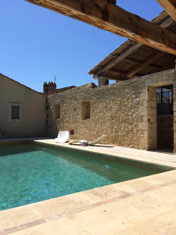 une piscine devant un bâtiment en pierre dans l'établissement Les Toiles du 15, à Montaren-et-Saint-Médiers