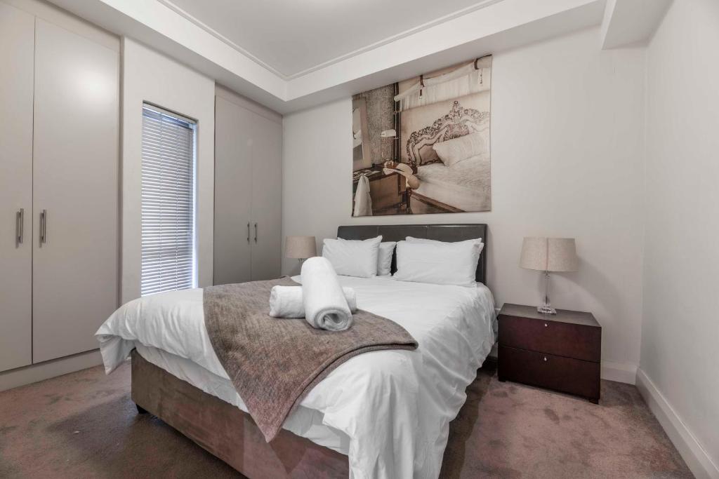 a white bedroom with a large bed and a window at 706 Canal Quays in Cape Town