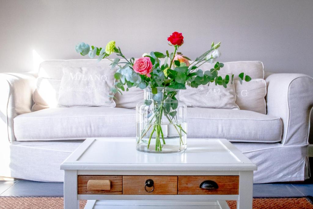 a vase of flowers on a coffee table in front of a couch at Van Doremaele Luxury Guesthouse in Velddriel