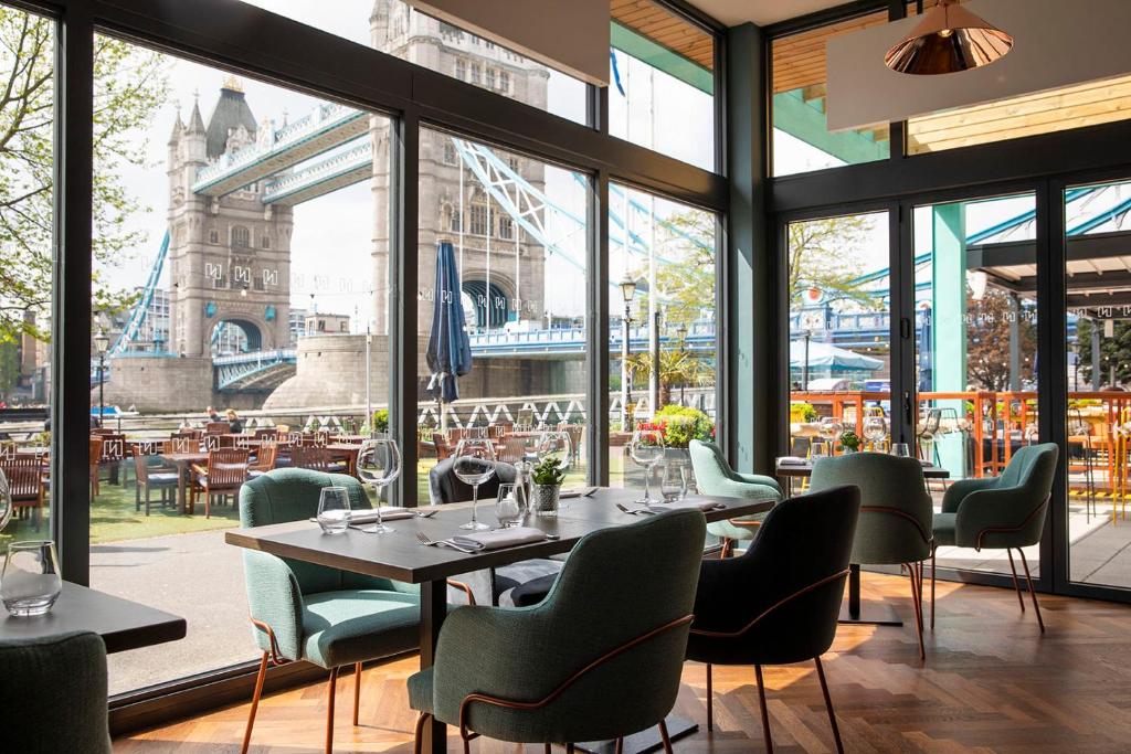 a restaurant with tables and chairs and large windows at The Tower Hotel, by Thistle in London