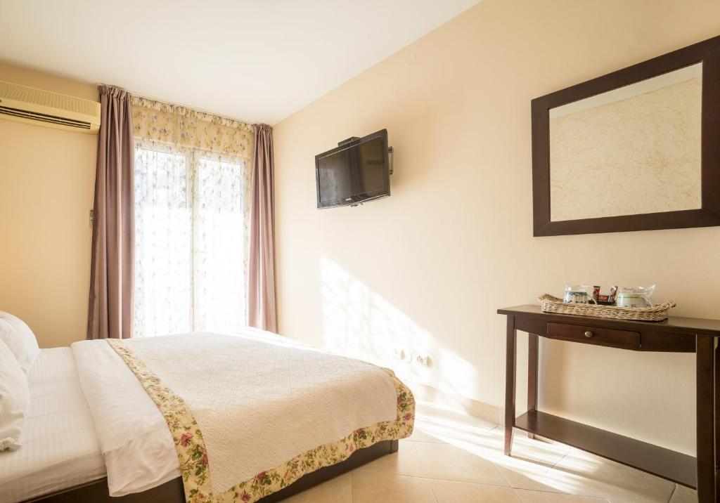 a bedroom with a bed and a television on the wall at Hotel Villa Perla Di Mare in Budva