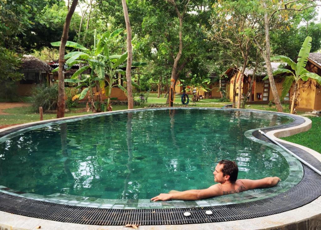 Ein Mann, der im Schwimmbad liegt. in der Unterkunft Sat Nam Village Eco-Hotel in Sigiriya