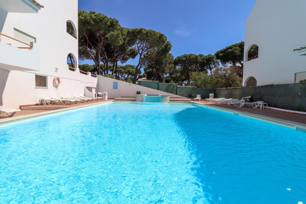 a large swimming pool with blue water in front of a building at Green paradise T2 apartment with pool top floor in Albufeira