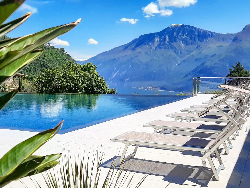 a row of lounge chairs next to a body of water at 3MÙZEN apartments in Tremosine Sul Garda