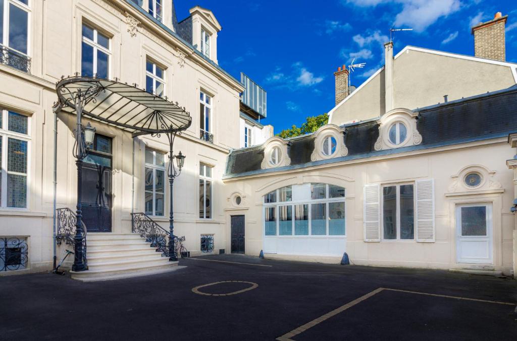 Un grand bâtiment blanc avec un escalier se trouve devant. dans l'établissement La Noctambulle Forum, à Reims