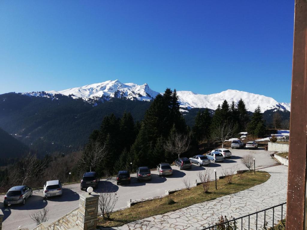 um monte de carros estacionados num parque de estacionamento com montanhas cobertas de neve em Ξενοδοχείο ΜΑΓΚΙΩΣΗ em Neraïdochóri