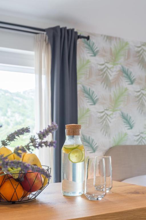 a bottle of vinegar and two glasses on a table at Hvar Top View Apartments in Hvar