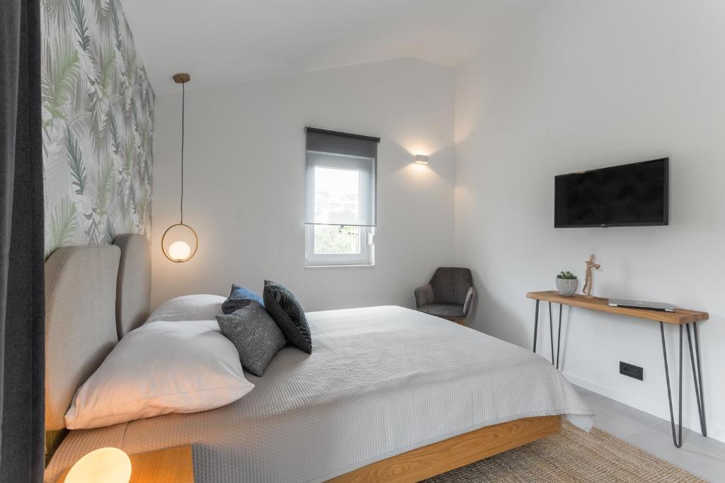 a white bedroom with a bed and a desk at Hvar Top View Apartments in Hvar