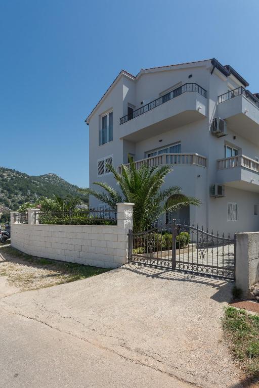 a white building with a fence in front of it at Hvar Top View Apartments in Hvar