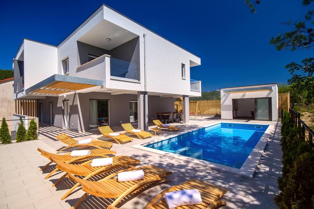 uma casa branca com piscina e cadeiras em Villa Tela em Kučiće