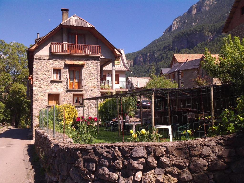 una casa de piedra con una valla delante de ella en Pensión Pallaruelo, en Saravillo