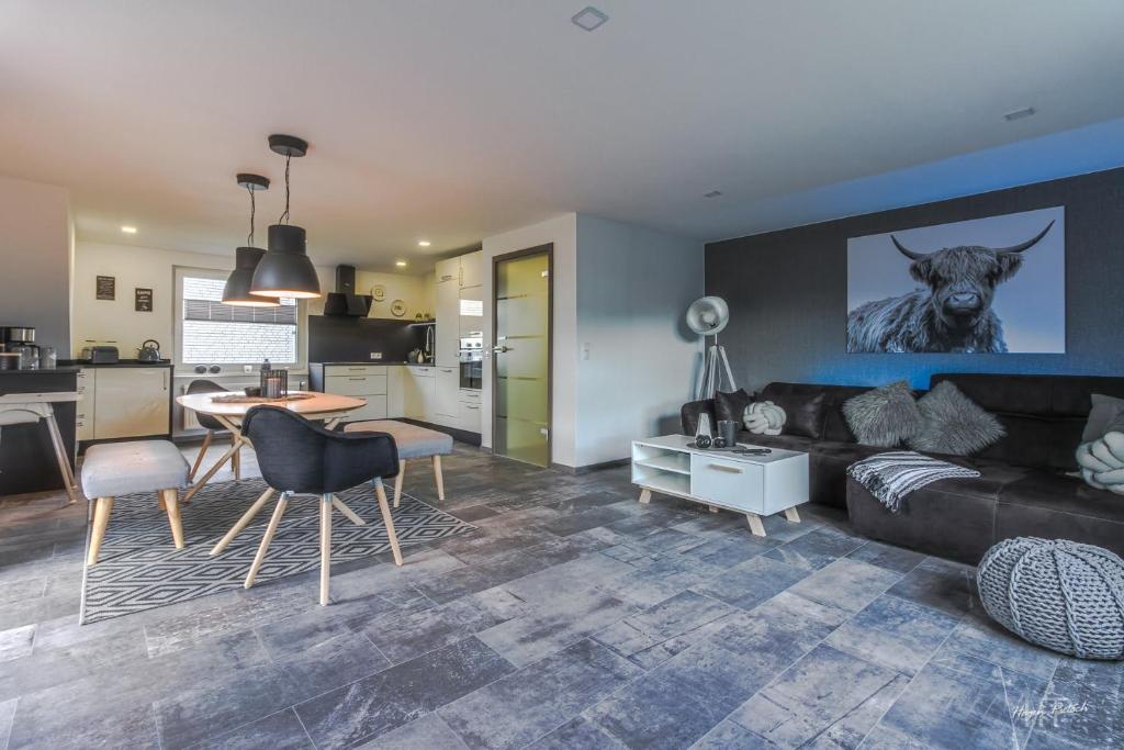 Ferienwohnung Traumblick في Wolfshagen: غرفة معيشة مع أريكة سوداء ومطبخ