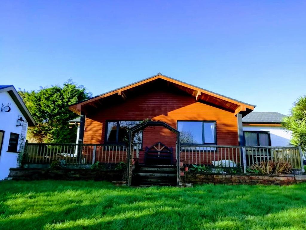 uma cabana de madeira com um alpendre e relva verde em Hunters Lodge B&B em Waterford