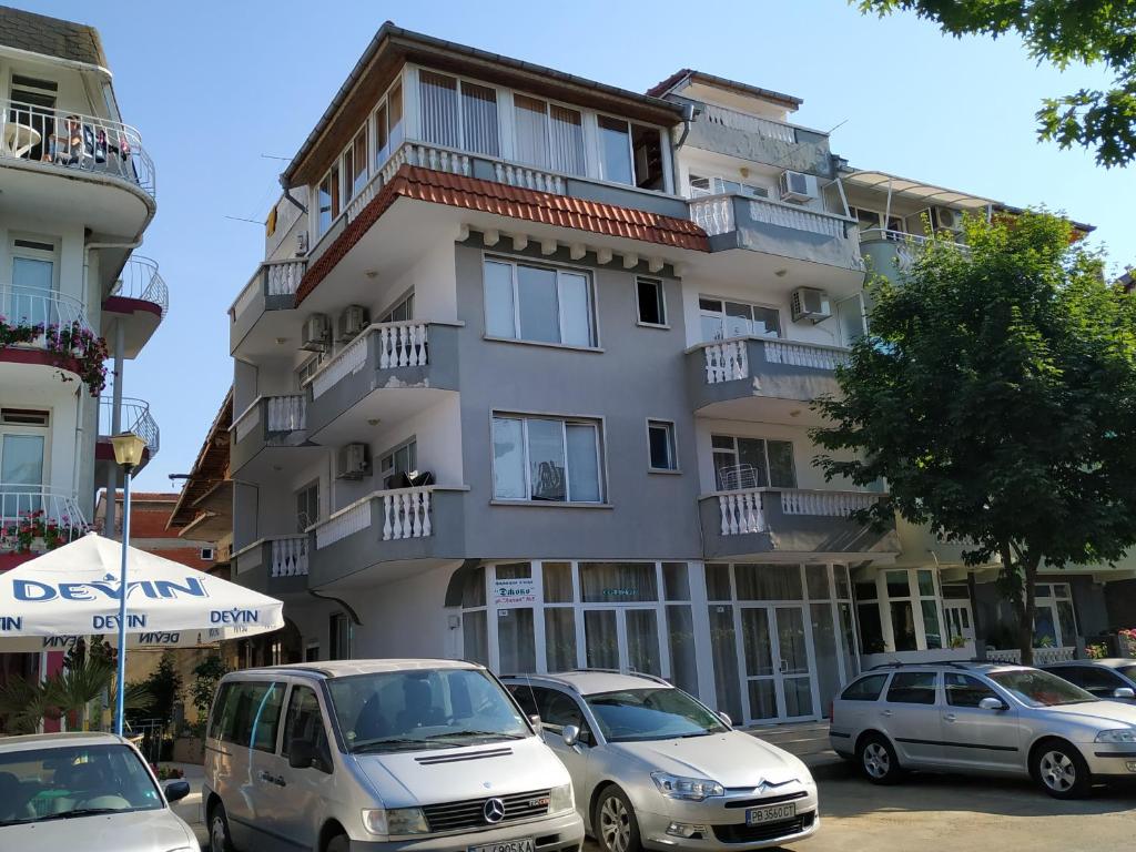 a tall building with cars parked in front of it at Фамилна къща Джоко in Kiten