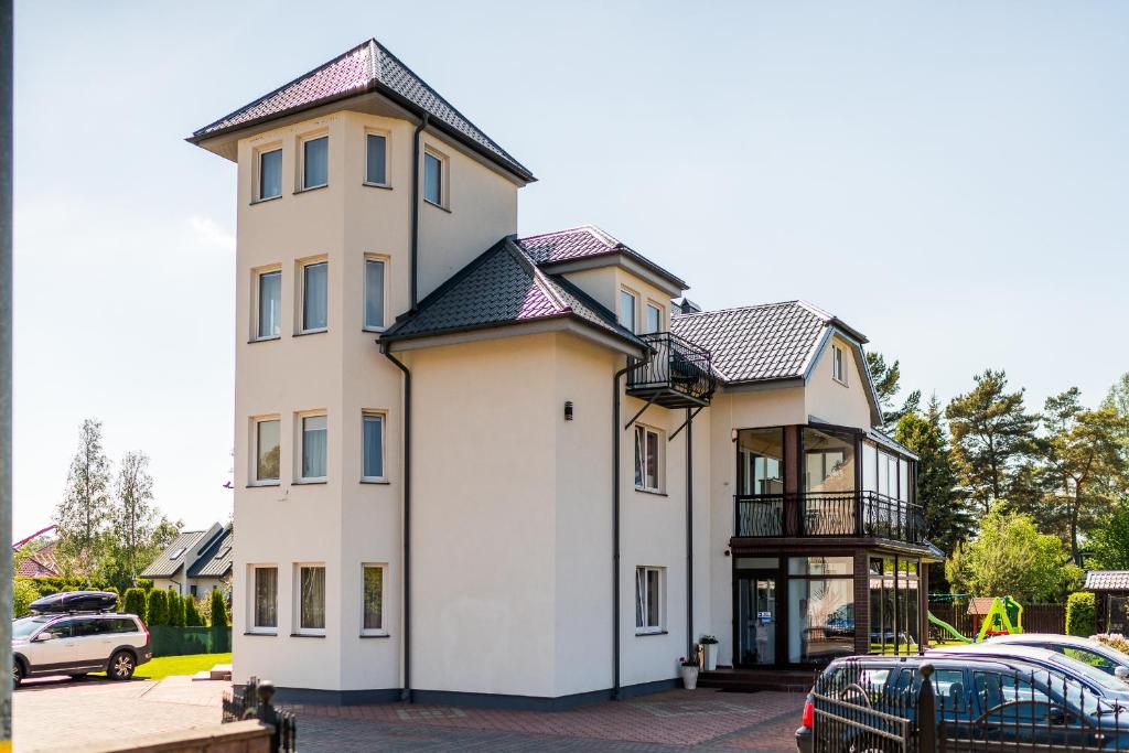 a white house with a black roof at Apartamenty i pokoje Sosnowa 4 Dębki in Dębki