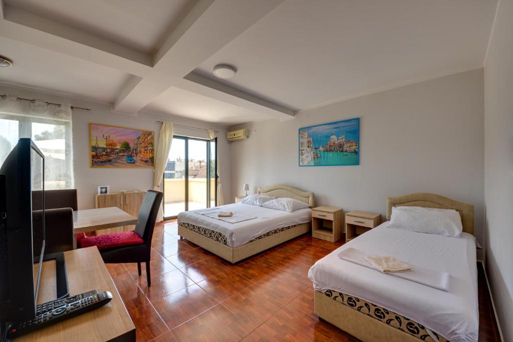 a room with two beds and a desk and a television at Apartmani Bozinovic in Herceg-Novi