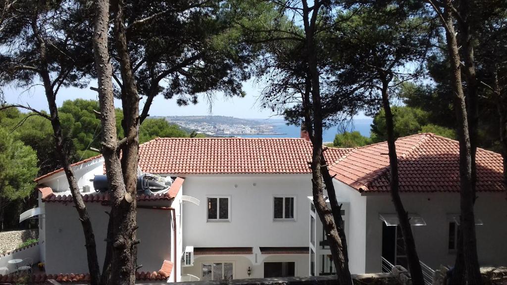a white house with a red roof and trees at Dimora Villa Serena Porto Selvaggio in Santa Caterina di Nardò