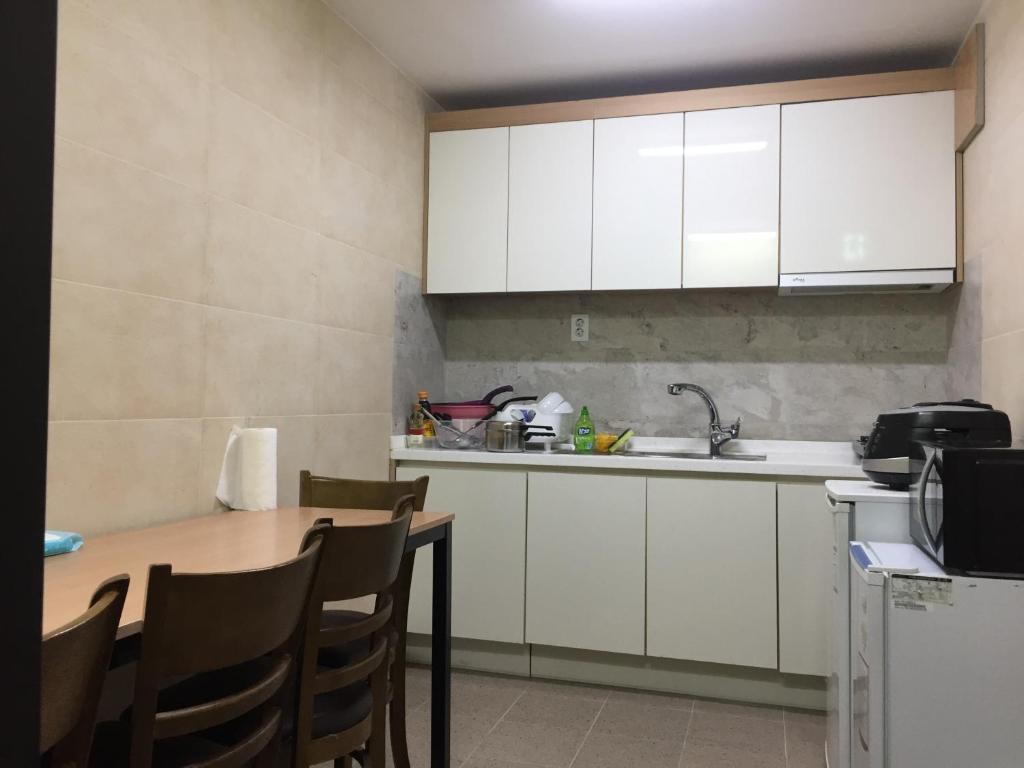 uma cozinha com armários brancos e uma mesa com cadeiras em The Core Albergue em Seul