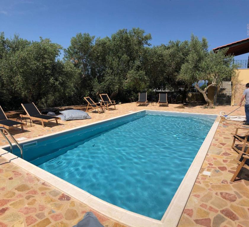 a swimming pool with blue water and chairs and trees at Villa Gaia in Monemvasia