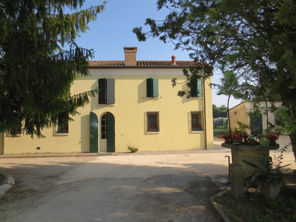 Casa amarilla grande con ventanas con contraventanas verdes en Borgo Tarapino, en Ferrara