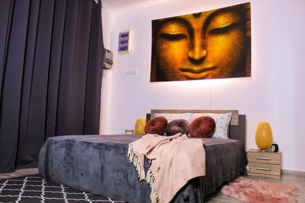 a bedroom with a bed with a painting of a face at Nirvana Apartament in Bucharest