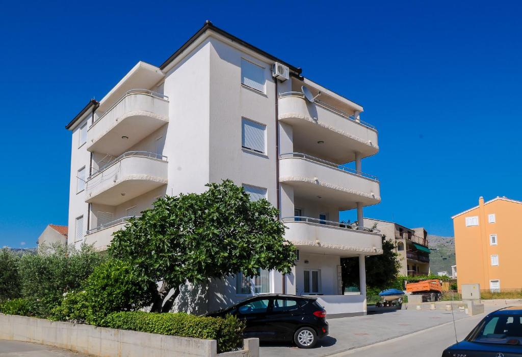 un bâtiment blanc avec des voitures garées devant lui dans l'établissement Apartment Neva, à Split