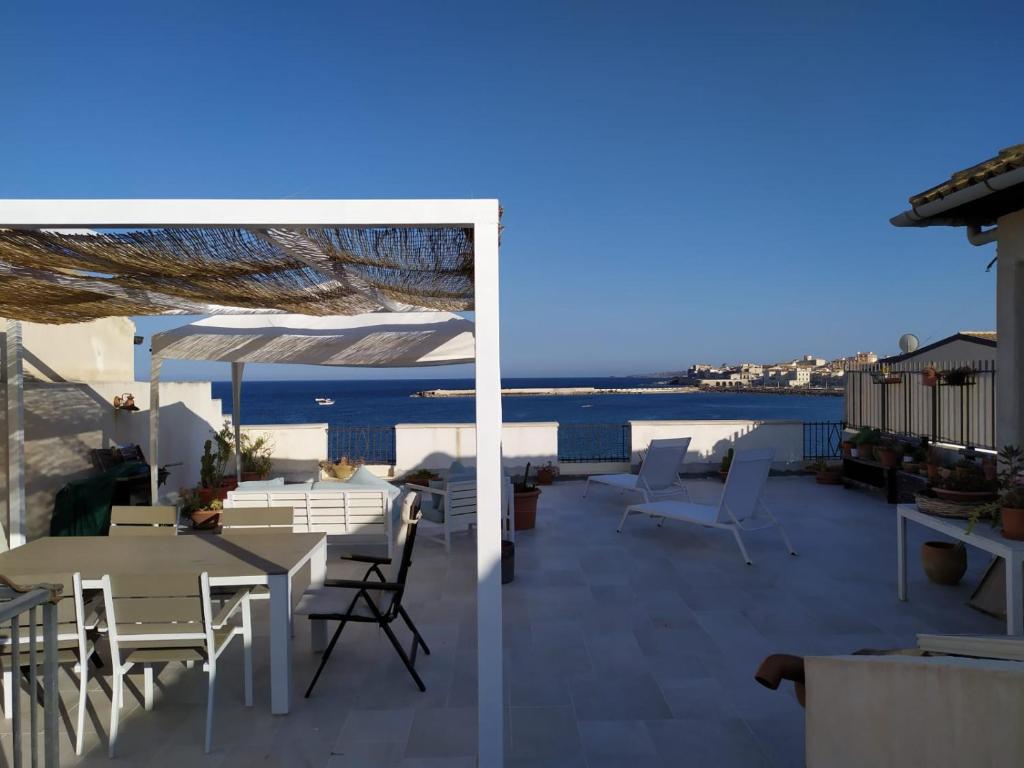 un patio con mesas y sillas y vistas al agua en Veranda Vista Mare, en Siracusa