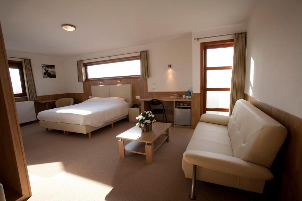een hotelkamer met een bed en een bank bij Hotel Chamdor in Roeselare