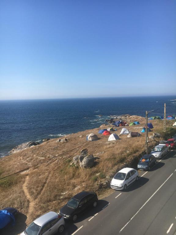 a group of cars parked on a road near the ocean at Apartamento Xardin in Muxia
