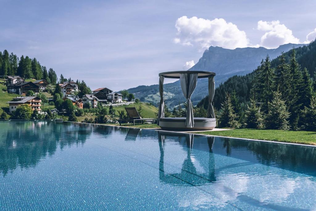 a pool of water with mountains in the background at Hotel Cristallo - Wellness Mountain Living in La Villa