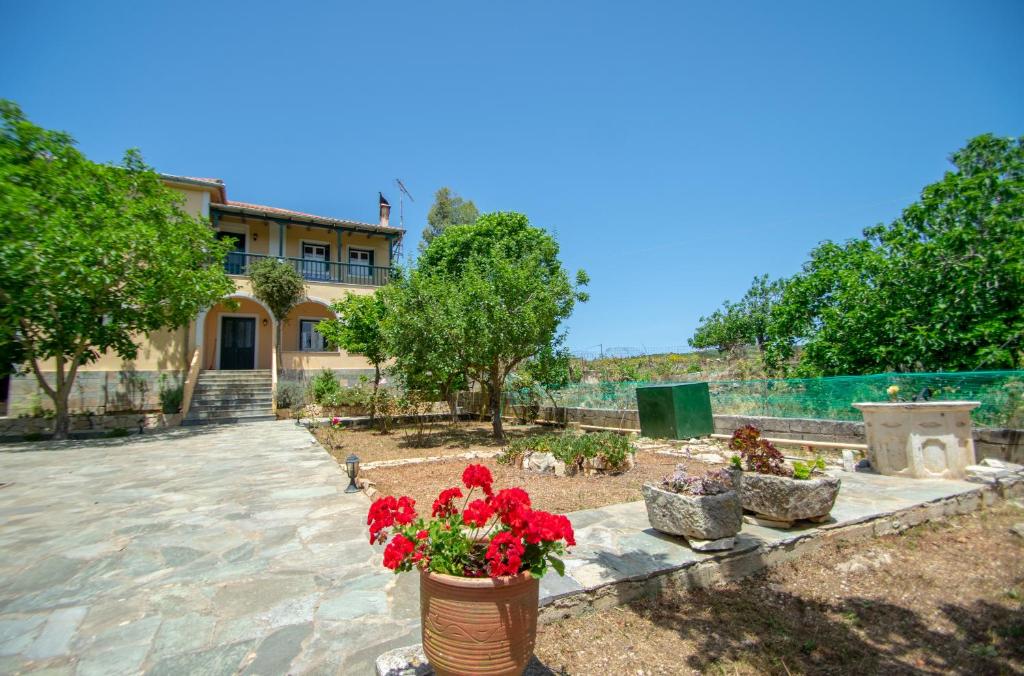une maison avec des fleurs rouges dans une cour dans l'établissement Casa Tsounis by "elite", à Volímai