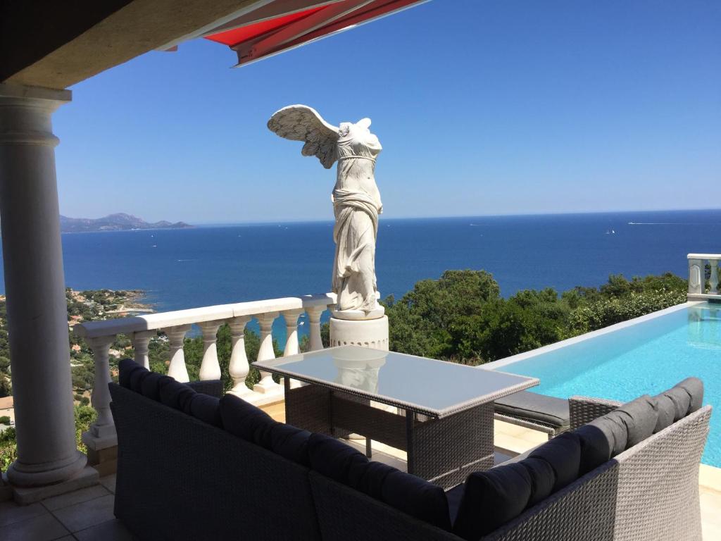 une statue d'un ange debout sur un balcon à côté d'une piscine dans l'établissement Villa Goonie, aux Issambres