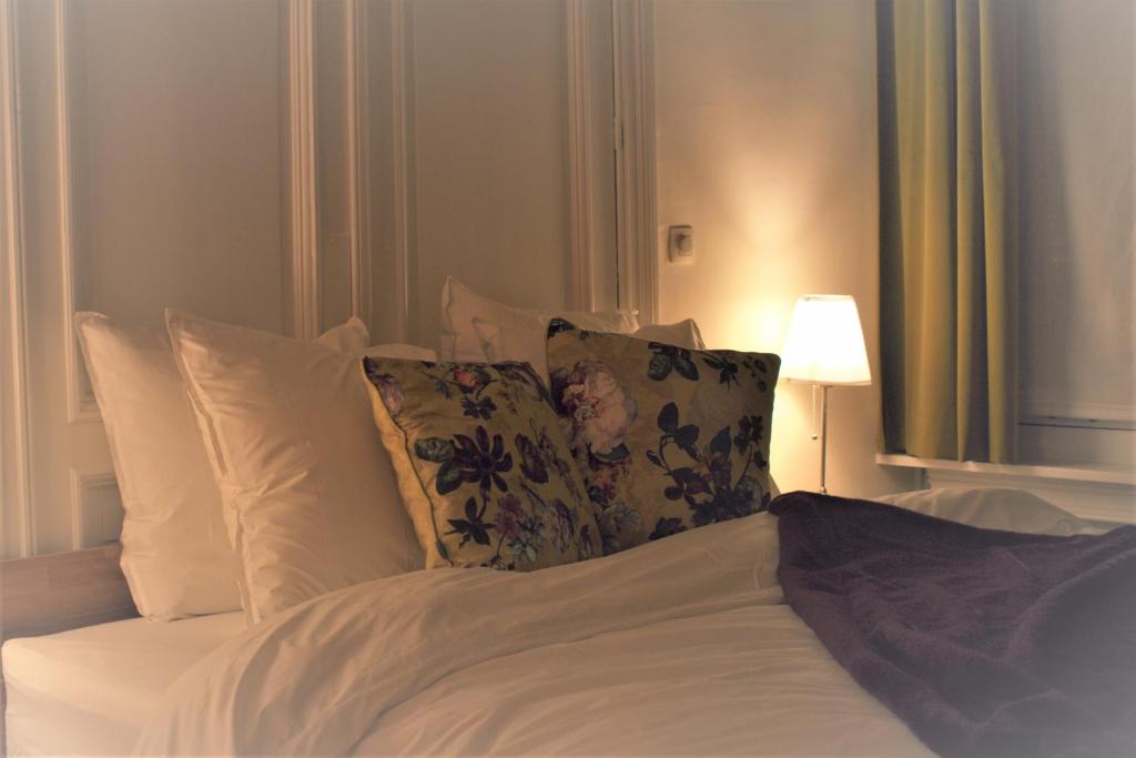 1 cama con sábanas y almohadas blancas y lámpara en Quiet apartment in Antwerp near parc - B&B InterMezzo - business & leisure, en Amberes