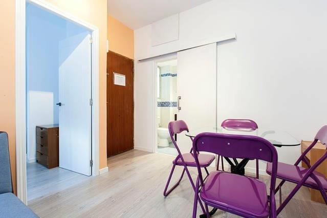 a room with purple chairs and a table and a door at Centro Madrid Rio - Monederos C in Madrid