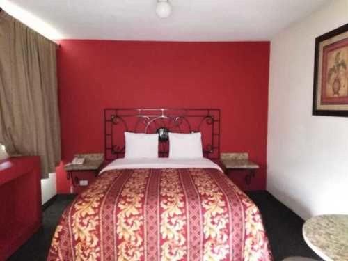 1 dormitorio rojo con 1 cama con pared roja en Hotel Descanso Inn en Tijuana