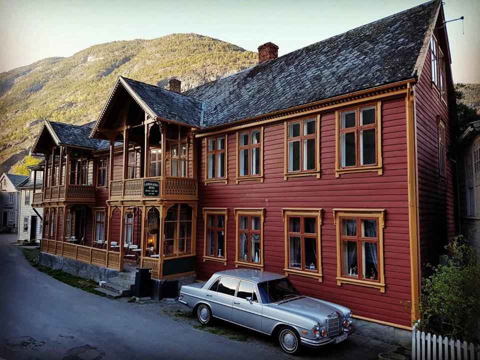 um carro velho estacionado em frente a um edifício de madeira em Lærdalsøren Motor Guesthouse em Lærdalsøyri